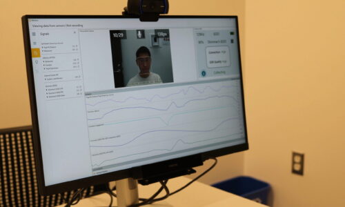 A monitor displaying eye-tracking and biometric data from a respondent. The screen shows graphs, data, and a webcam feed of the participant being analyzed.