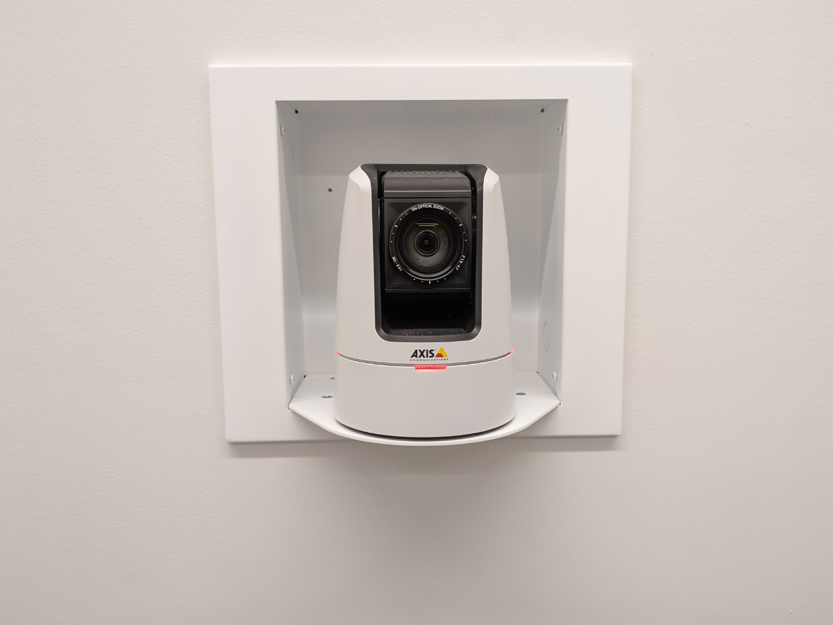 A security camera mounted within a white enclosure on a wall.